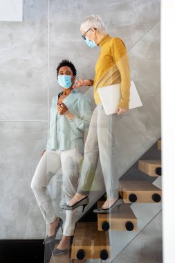 Başlangıçta çalışan kadınlar maske takıyor, yaratıcı projeler, modern takım çalışması ve başarı için güvenli iş kültürü konusunda dizüstü bilgisayarla işbirliği yapıyorlar.