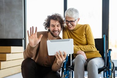 Farklı profesyonellerden oluşan bir grubun birlikte çalıştığı parlak, çağdaş bir ofis. Tekerlekli sandalye kullanan birini de kapsar.