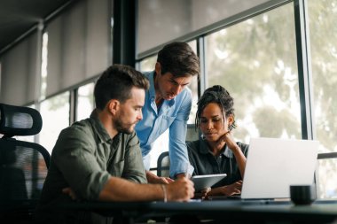 Çeşitli, yetenekli bir takım, bir iş toplantısı sırasında parlak bir ofis alanında etkili bir şekilde işbirliği yapar. Birlikte çalışan başarılı iş arkadaşlarından oluşan yaratıcı bir grup