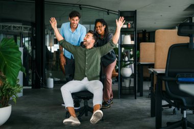 Bin yıllık çok ırklı takım insanlar eğlenmek oda ofis, heyecanlı farklı çalışanlar iş kopma komik faaliyet zevk gülüyor koltuklarda sürme yaratıcı samimi işçiler birlikte oyun oynamak