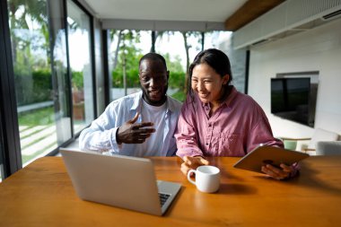 Başarılı çeşitlilik, çok ırklı bağımsız çift, birlikte dizüstü bilgisayarda çalışarak, tropik iklimin huzurlu ortamının tadını çıkarıyor..