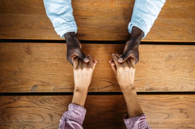 Farklı etnik kökenlere sahip insanlar arasında bir tokalaşma, güveni, uyumu, ait olmayı ve birliği sembolize eder. Mutlu ve dengeli bir çift el ele tutuşuyor..