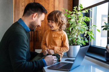 Babalık ve uzak iş. Yanında çocuk oynarken evde çalışan genç ve yakışıklı bekar bir baba.