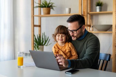 Evde dizüstü bilgisayar kullanan, video görüşmesinde sanal parti yapan, ekommerce ailesi ile online alışveriş yapan tatlı, heyecanlı, küçük çocuklu mutlu bekar ebeveyn.