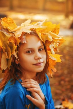 Bir kız okul çağındaki güzel güneşli Güz Park bir çelenk yaprakların portresi.