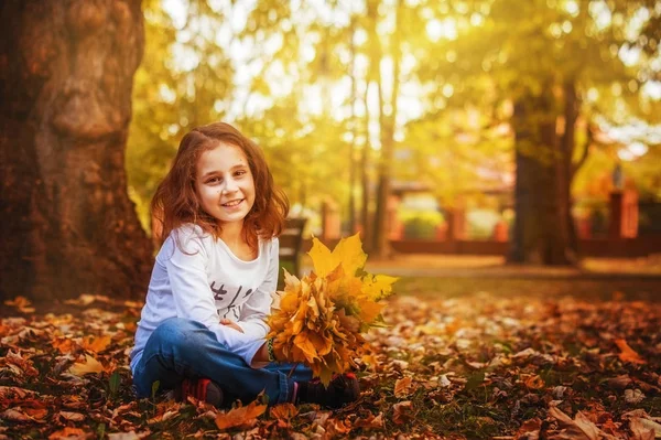 Dziecko Dziewczynka Siedzi Trawie Jesienią Park Liści Ręku Marzy — Zdjęcie stockowe