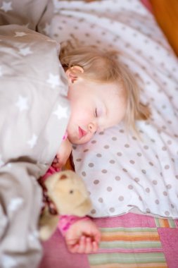 Bir oyuncak ayı ile uyuyan bebek.