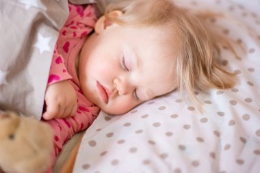 Bir oyuncak ayı ile uyuyan bebek.