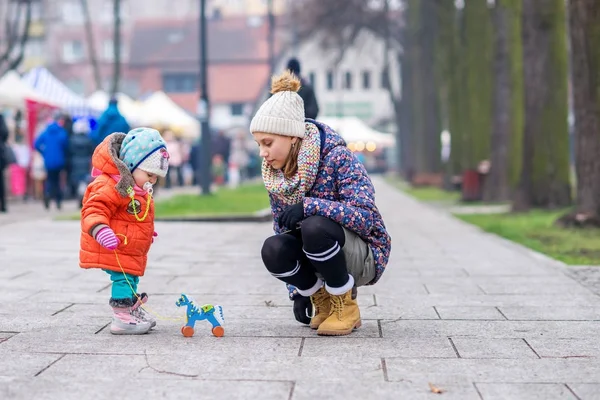 Çocuk ve ablası sokak soğuk havalarda tahtadan bir at ile oynamak.