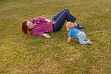 Bebek annesiyle çimenlerin üzerinde oynarken ilk yıl.