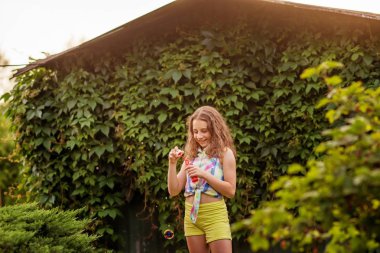 Kabarcıklar yaz bahçede günbatımında üfleme kız çocuk.