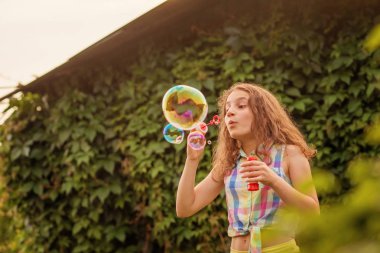 Kabarcıklar yaz bahçede günbatımında üfleme kız çocuk.