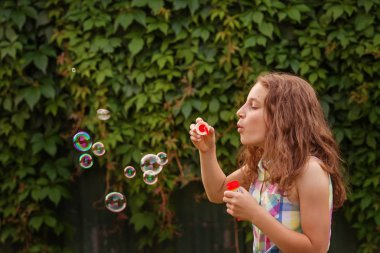 Kabarcıklar yaz bahçede günbatımında üfleme kız çocuk.