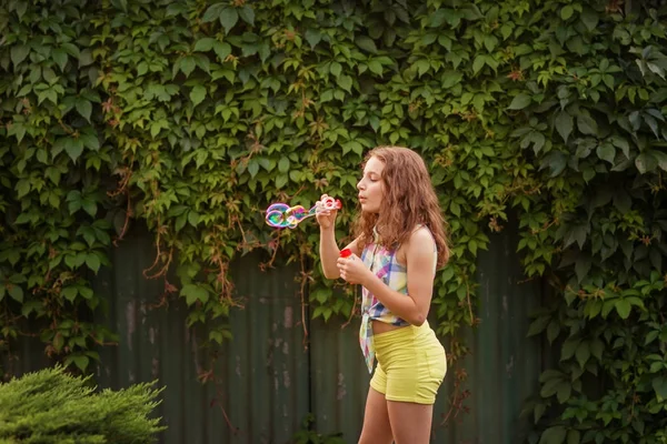Kabarcıklar yaz bahçede günbatımında üfleme kız çocuk.