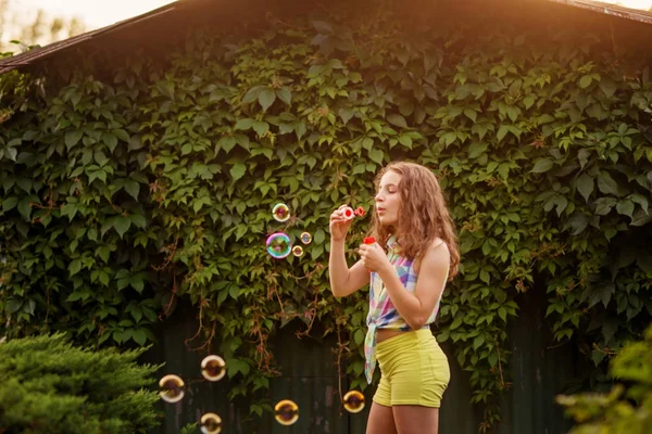 Kabarcıklar yaz bahçede günbatımında üfleme kız çocuk.