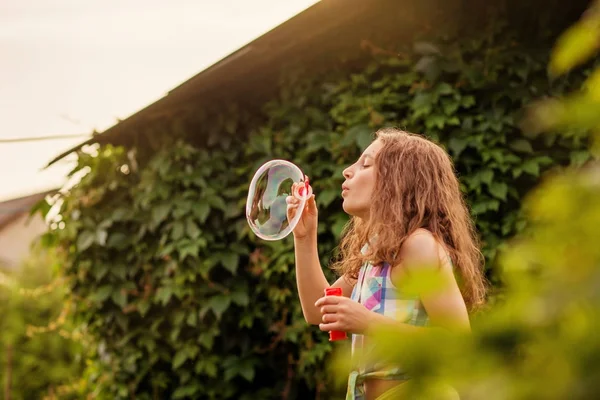 Kabarcıklar yaz bahçede günbatımında üfleme kız çocuk.