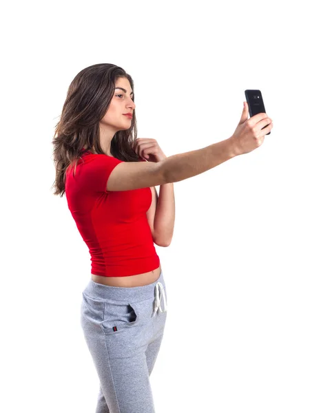 在白色背景使用移动电话的开朗吸引年轻女运动员 — 图库照片