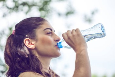 Güzel esmer kız içme suyu yaz yeşil park portresi.