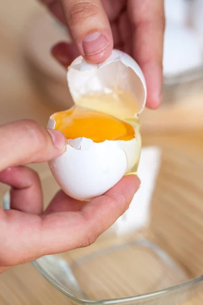 妇女手打破鸡蛋分开鸡蛋白和蛋黄 在背景蛋壳 — 图库照片
