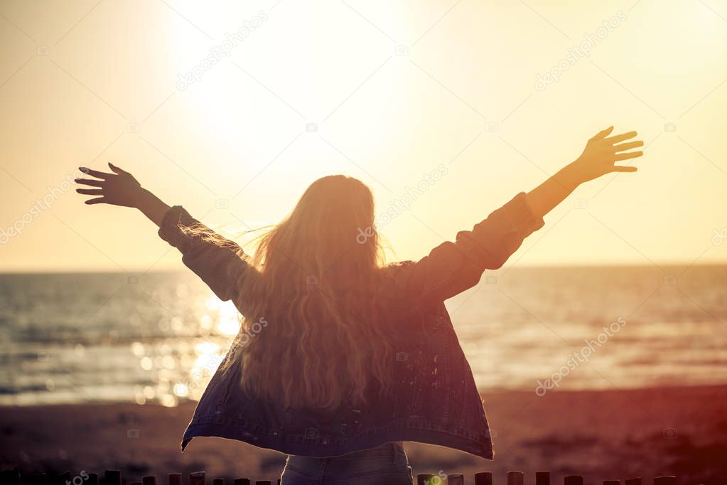 Beautiful woman on the beach enjoying fresh air freedom on sunset.