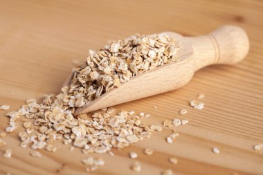 Ahşap tahta üzerinde bir kepçe ile ahşap bir kase yulaf gevreği.