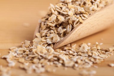 Ahşap tahta üzerinde bir kepçe ile ahşap bir kase yulaf gevreği.