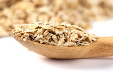 Beyaz tahta kaşıkla haddelenmiş yulaf yığını.