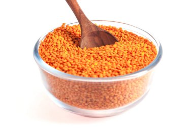 Beyaz arka plan üzerinde izole tahta kaşıkla cam kapta sarı mercimek.