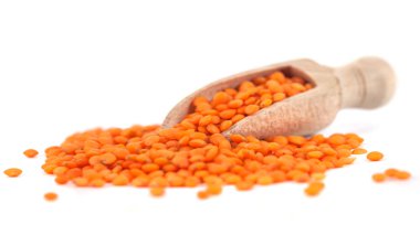 Tahta kaşıkta kırmızı mercimek, beyaz arka planda izole edilmiş.