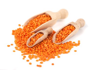 Tahta kaşıkta kırmızı mercimek, beyaz arka planda izole edilmiş.