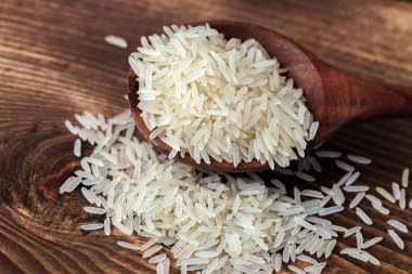 Tahta kaşık karanlık tablo arka plan üzerinde beyaz yasemin pirinç.