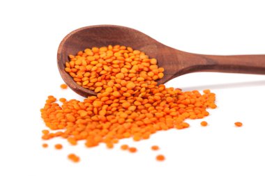 Tahta kaşıkta kırmızı mercimek, beyaz arka planda izole edilmiş..