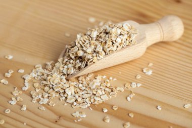 Ahşap tahta üzerinde bir kepçe ile ahşap bir kase yulaf gevreği.