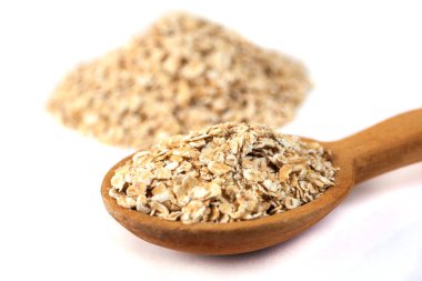 Beyaz tahta kaşıkla haddelenmiş yulaf yığını.