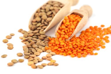 üzerinde tahta kaşık beyaz bir arka plan üzerinde izole kahverengi ve sarı mercimek Kuru.