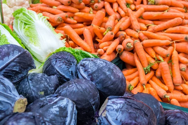 在农贸市场堆放的紫色卷心菜和胡萝卜 — 图库照片