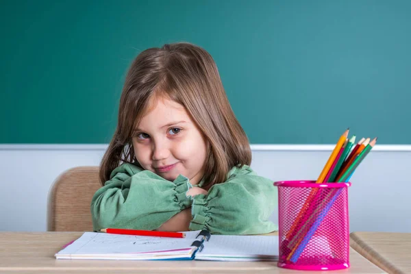 Kleines Hübsches Mädchen Sitzt Klassenzimmer Grauen Schreibtisch Und Posiert — Stockfoto