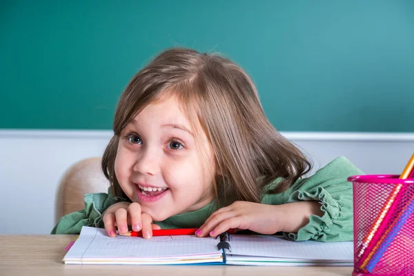 小さなかわいい女の子灰色机の教室で座っているとポーズ — ストック写真