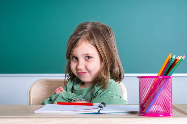 小さなかわいい女の子灰色机の教室で座っているとポーズ — ストック写真