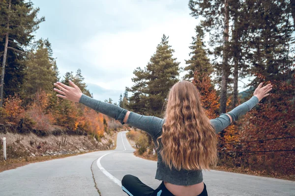 Svaneti, Gürcistan'daki boş bir yol ortasında oturan güzel sarışın kız.