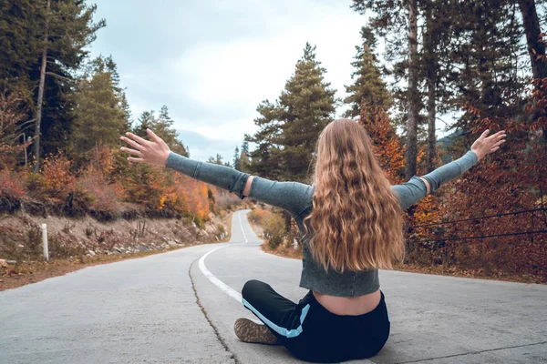 Svaneti, Gürcistan'daki boş bir yol ortasında oturan güzel sarışın kız.