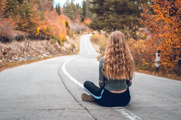 Svaneti, Gürcistan'daki boş bir yol ortasında oturan güzel sarışın kız.