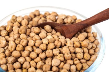 Beyaz arka planda, sağlıklı gıda tahta kaşıkla üzerinde cam kase nohut.