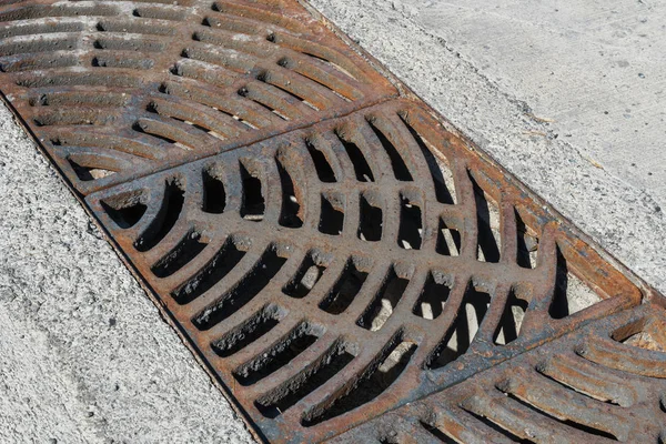 Drain of metal grate around with rough beton road — Stock Photo, Image