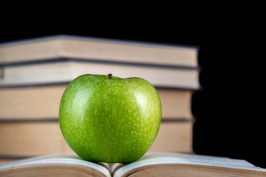 Siyah arka plan üzerinde kitap üzerinde yeşil elma
