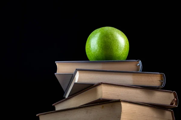 Siyah arka plan üzerinde kitap üzerinde yeşil elma — Stok fotoğraf