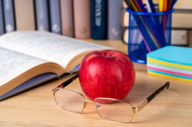 Okula dönüş. Kitap, Kırmızı elma, kalemler ve ahşap gözlük 