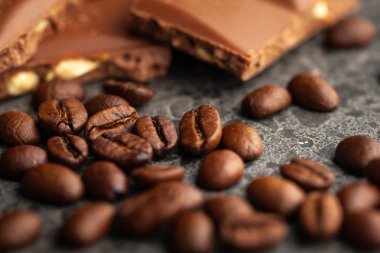 Gri arka planda kahve çekirdekleri ve koyu çikolata sır