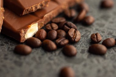 Gri arka planda kahve çekirdekleri ve koyu çikolata sır