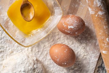 Pişirme tahtasında yumurta, tereyağı ve hamur ile beyaz un
